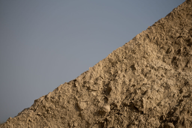 the rocky edge runs at a diagonal, separating the smooth gray-blue sky from the textured rock surface