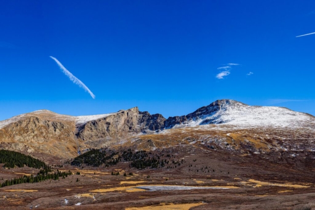 the rocky horizon of Mt. Bierstadt stands below a bright, clear blue sky